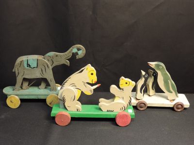 three wooden animals that are sitting on top of a toy car