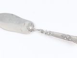 an old silver spoon with a handle on a white surface