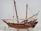 a wooden model of a sail boat on a white surface