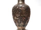 un vase en argent posé sur une surface blanche