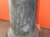 a black marble vase sitting on top of a wooden stand