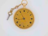 a gold pocket watch with a key attached to it