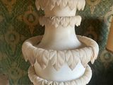 a white vase sitting on top of a table next to a lamp