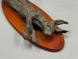 a sculpture of a dog laying on top of a wooden board