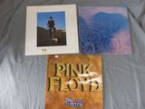 two pink floyd albums on a bed with a blue blanket