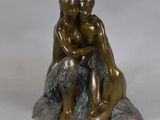 statue en bronze représentant un couple assis sur un rocher