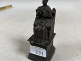 une petite statue représentant une femme assise sur une chaise