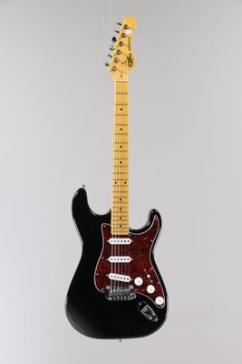 a black electric guitar hanging from a white wall