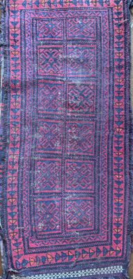a blue and pink rug on a wooden floor next to a wall