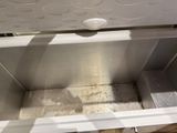underside view of a white chest freezer with dirt on the bottom
