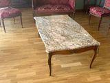 une table basse au plateau en marbre au milieu du salon