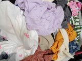 a pile of clothes sitting in a suitcase on the floor