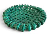 un gros plan d'un bol orné de perles vertes posé sur une surface blanche