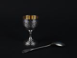 a silver goblet and spoon on a black background