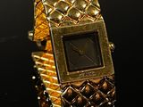 une image représentant une montre-bracelet en or posée sur une surface noire