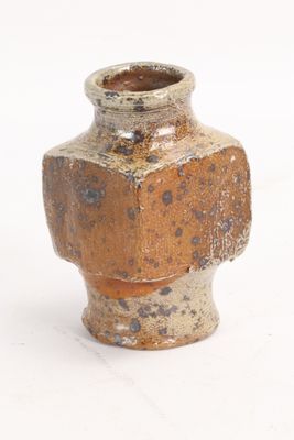 un petit vase posé sur une surface blanche
