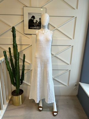 une robe blanche posée sur un mannequin, à côté d'un cactus en pot