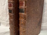 two old books sitting on top of each other on a white surface