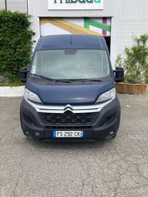 Une camionnette bleue est garée devant un immeuble.