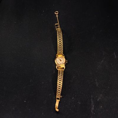 une montre en or posée sur un tissu noir, entourée d'une chaîne