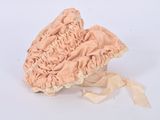 a pink bonnet with a ribbon around it on a white surface
