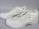 une paire de baskets blanches avec des lacets blancs, posée sur une surface blanche