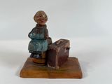 a statue of a woman sitting on top of a suitcase