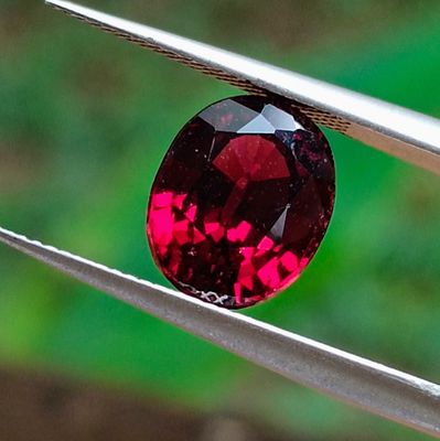 a close up of a red diamond being held by a pair of pliers