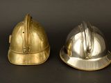 pair of antique brass fire helmets on black background with black background