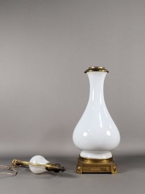 une paire de vases blancs et dorés posés sur une table, à côté d'une petite lampe