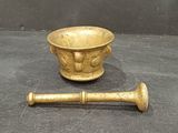 a small brass bowl and a wooden stick on the floor