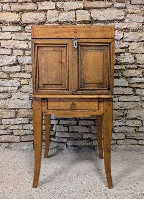 an old wooden cabinet sitting on top of a table next to a brick wall