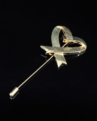 une image représentant une broche en or ornée d'un ruban et d'un nœud