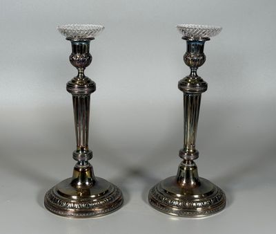deux bougeoirs en argent posés l'un à côté de l'autre sur une table