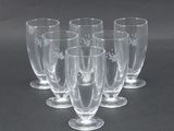 six verres à vin transparents sont alignés sur une surface noire