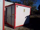 des toilettes portables rouges et blanches posées dans l'herbe