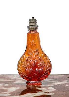 une bouteille en verre rouge posée sur une table en bois