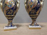 two vases sitting on a table with a wall in the background