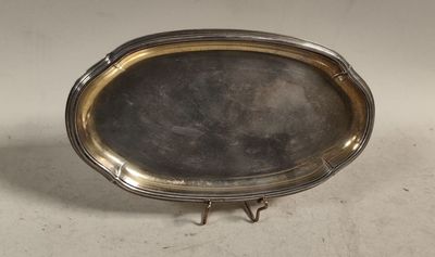 un plat en argent bordé d’or, posé sur un socle, sur un fond blanc