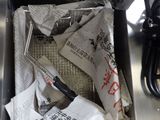 a trash can with newspaper and scissors inside of it