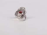 a close up of a silver ring with a red stone in it