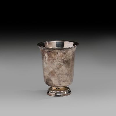 an antique silver cup on a pedestal with a black background
