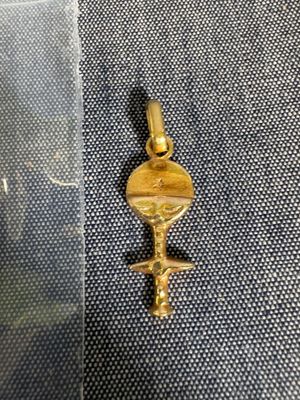 une photo d'un pendentif en forme de clé plaqué or posé sur un tissu bleu