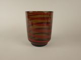 a red and brown glass cup on a white surface