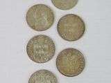 six different coins are arranged in a row on a white surface