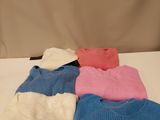 several sweaters are stacked on top of each other on a table
