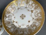 a white and gold cup and saucer sitting on a table