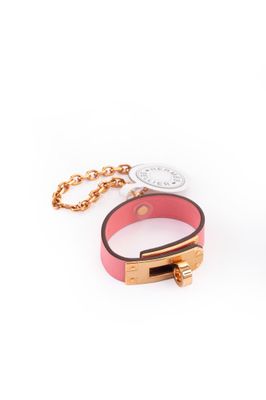 un bracelet en cuir rose muni d'un fermoir doré fixé à une chaîne
