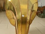 a large gold vase on a wooden stand in a room