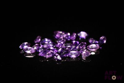un gros plan sur un tas de pierres précieuses violettes posées sur une surface noire